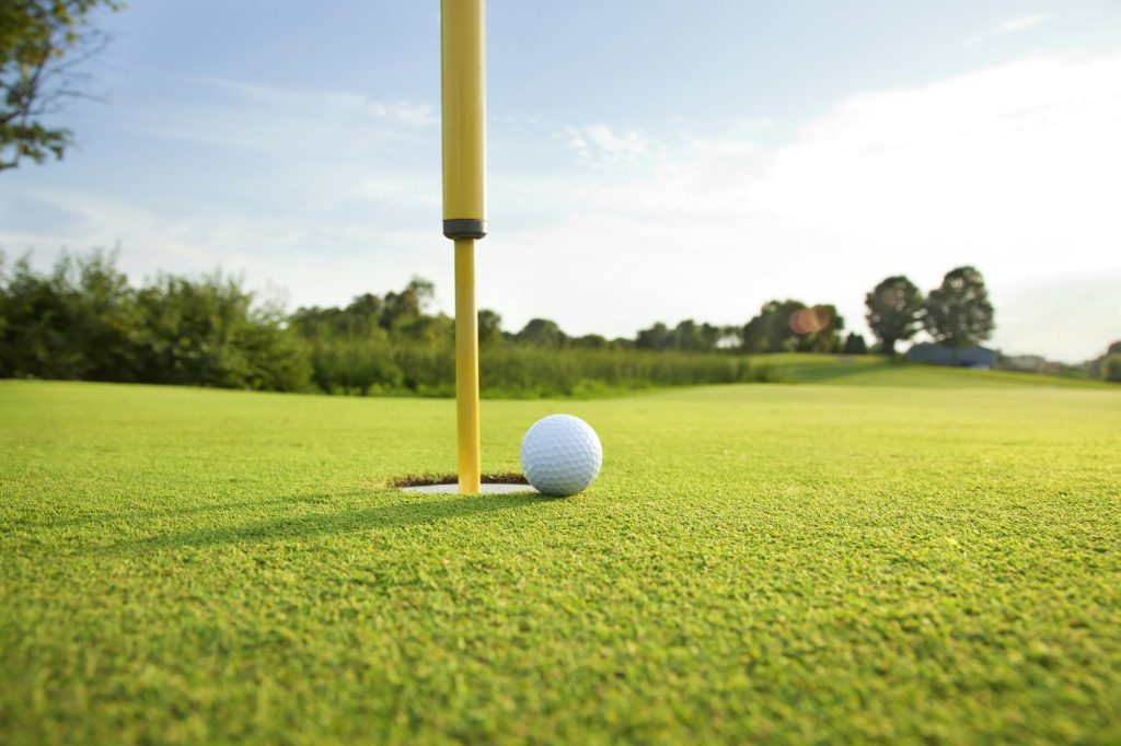 Close up of golf ball near hole with pin on golf green